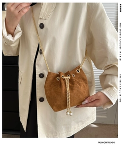 Detailaufnahme der braunen Cord-Beuteltasche mit Goldkette und Perlen-Kordelzug-Details