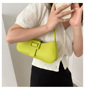 Detail of neon green shoulder bag featuring a large square buckle and smooth leather