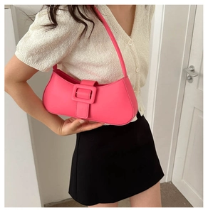 Detailed view of magenta crossbody bag featuring a large decorative buckle on a model