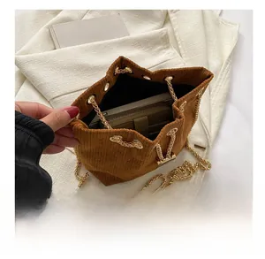 Makroansicht der Cord-Textur und Perlendetail am Kordelzug der braunen Beuteltasche