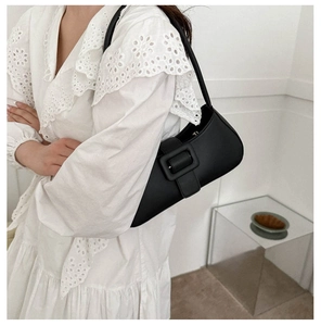 Chic black leather underarm bag with square buckle shown in a minimalist style setting