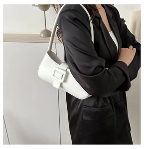 Detail of white faux leather underarm bag with large square buckle on black blazer