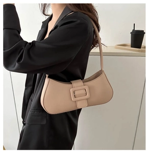 Close-up of minimalist beige leather underarm bag with a decorative square buckle detail
