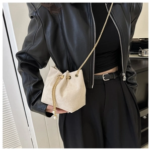 Detail der cremeweißen Cord-Beuteltasche mit goldener Kette und Perlen-Kordelzug-Verzierung