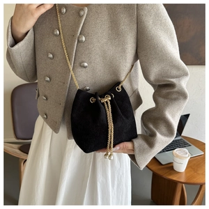 Detail der schwarzen Cord-Beuteltasche mit Goldkette und Perlen-Kordelzug-Anhängern