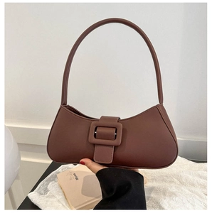 Detail of a dark brown leather underarm bag featuring a large square decorative buckle