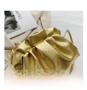 Macro shot of gold cloud pouch bag showing pleated texture and glossy metallic finish