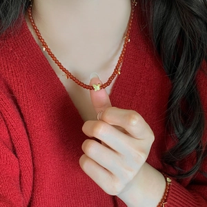 Collier en agate rouge de style chinois avec pendentifs papillons dorés sur pull rouge