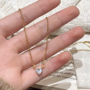 Gold-plated minimalist necklace with a sparkling heart-shaped zircon pendant held by hand