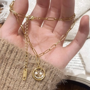 Gros plan du collier visage souriant doré avec yeux en perles et détails en zircons brillants