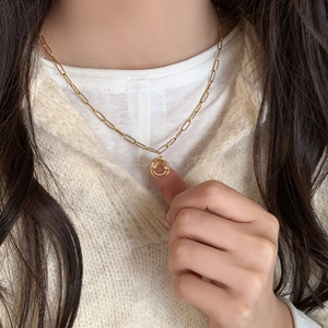 Collier chaîne trombone dorée avec pendentif smiley en perles porté par un modèle