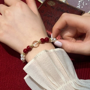 Handmade red agate and pearl beaded bracelet with gold-plated accents on a luxury wrist display