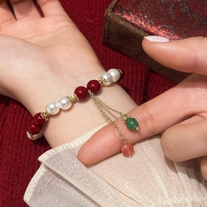 Red agate and pearl beaded bracelet with gold accents shown on a person wrist