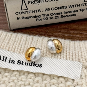 Macro shot of gold and silver mixed-metal oval earrings with a brushed texture detail