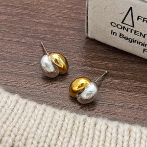 Detail of two-tone gold and silver ball earrings on a dark wood background