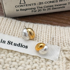 Detail of mixed-metal sphere earrings with gold and silver texture on knit fabric