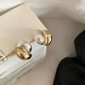 Detailed close-up of mixed metal earrings with brushed and polished textures