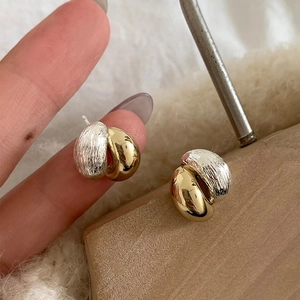 Minimalist gold and silver two-tone earrings with twisted metal texture and polished finish