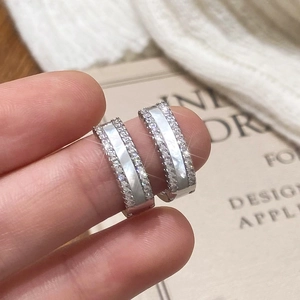 Détail macro de boucles d'oreilles C en argent avec nacre et zircons étincelants