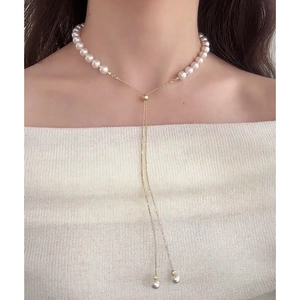 Elegant white pearl necklace with adjustable gold tassel and sliding metal clasp on model