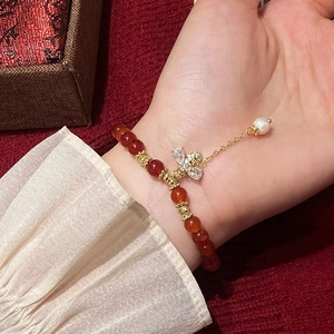 Bracelet en cornaline avec pendentif nœud et pompon de perle d'eau douce sur un poignet