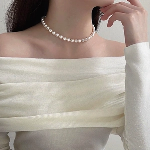 Elegant white pearl necklace with glossy finish shown on model with white knit sweater