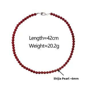 Detail of red faux pearl necklace featuring a 42cm length and secure metal clasp