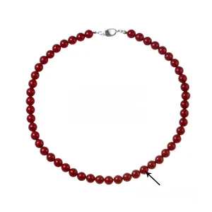 Detail of red faux pearl necklace featuring polished round beads and silver oval clasp