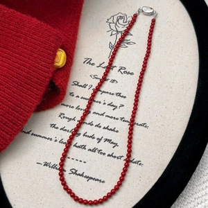 Elegant red beaded pearl necklace with silver clasp styled on aesthetic literary prop