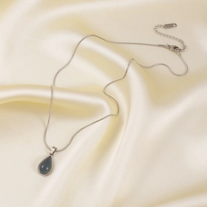 Silver stainless steel snake chain necklace with teardrop blue stone on silk fabric
