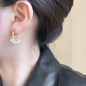Boucles d'oreilles créoles dorées avec pampilles de perles blanches portées par un mannequin