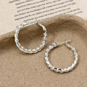 Detailed close-up of silver twisted rope hoop earrings on vintage textured paper background