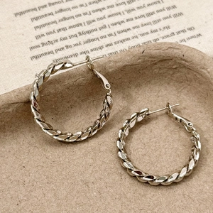 Close-up of silver twist texture hoop earrings on vintage aesthetic paper background