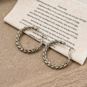 Silver twisted hoop earrings with geometric texture on minimalist background