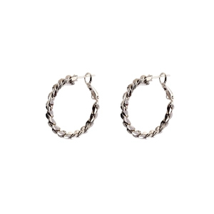 Macro shot of silver hoop earrings featuring a unique twisted woven texture and high polish