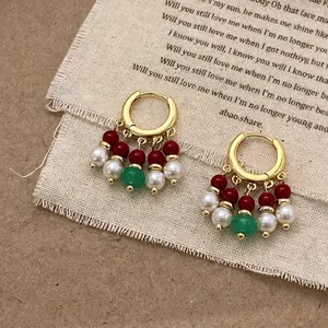 Détail de boucles d'oreilles rétro dorées avec agate verte et perles sur lin