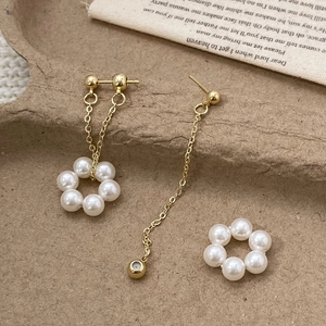 Asymmetric gold pearl earrings with chain fringe set displayed on vintage paper background