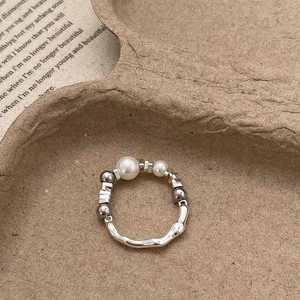 Detailed close-up of handmade pearl beaded ring with silver textured metal elements