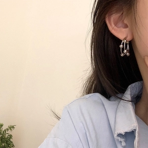 Close-up of minimalist layered beaded hoop earrings on model with metallic finish