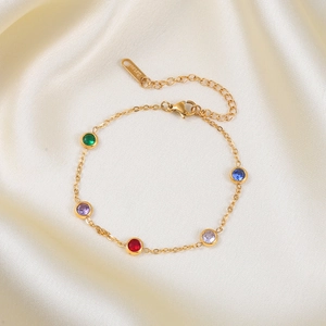 Gold stainless steel necklace with five colorful round zircons on a white silk background
