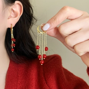 Elegant gold chain fringe earrings with red pearls worn by model in red sweater
