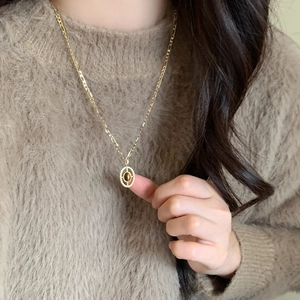 Golden Figaro chain necklace with oval tiger eye pendant worn on beige sweater
