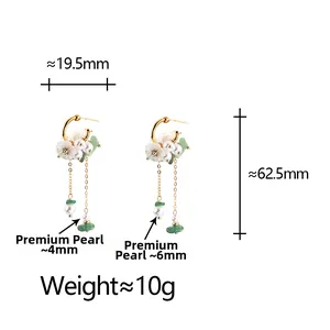 Detailed view of elegant gold tassel earrings with white flowers and green crystal beads