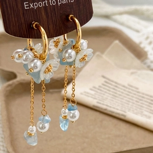 Elegant gold flower tassel earrings with blue stones and pearls on display card