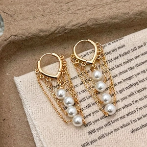 Boucles d'oreilles vintage en or avec glands de perles sur un fond texturé élégant