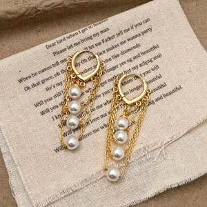 Boucles d'oreilles vintage en perles dorées avec franges élégantes sur tissu rustique