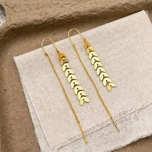 Close-up of golden leaf tassel earrings on rustic burlap background with lyrics