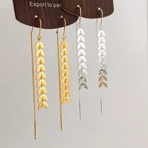 Elegant gold and silver leaf tassel threader earrings shown on a wooden display board