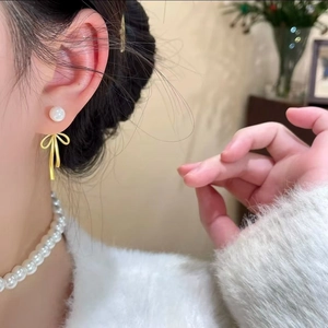 Ensemble élégant de boucles d'oreilles nœud doré et perles avec collier assorti sur mannequin