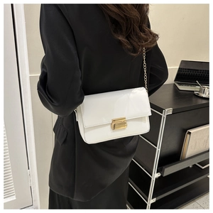 Chic white leather shoulder bag with gold metal clasp and chain strap on a model